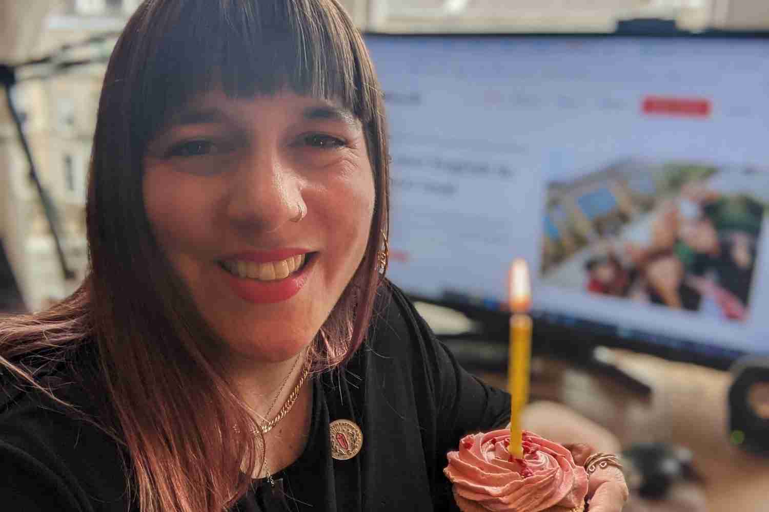 Photo of teacher smiling with a cupcake in front of a computer 