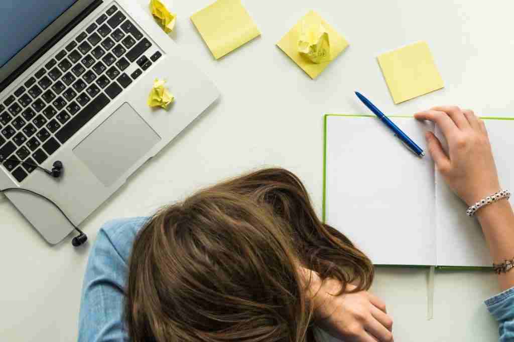 Women with language burn out lying face down on her desk. 